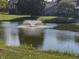 Scenic view of a tranquil pond with a fountain, surrounded by mature trees and well-maintained landscaping at 9464 Fordham St, Indianapolis, IN 46268