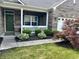 Charming front porch with manicured garden, green door, and a Welcome sign at 9752 Brook Wood Dr, McCordsville, IN 46055