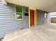 Close-up of a house's front porch with a red front door, colorful trim and gray siding at 980 Edgemont Ave, Indianapolis, IN 46208
