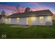 A serene backyard featuring a well-maintained lawn and patio with sliding glass door at sunset at 9856 Commonwealth Dr, Fishers, IN 46038