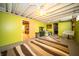 Finished basement with vibrant green walls, striped rug, and doorway to unfinished area at 1019 N Lesley Ave, Indianapolis, IN 46219