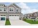View of townhome with gray siding, two-car garage, landscaping, and other homes in the distance at 1239 Newton St, Avon, IN 46123