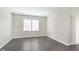 Bright, empty room with gray wood floors, neutral walls, and sliding glass door at 1239 Newton St, Avon, IN 46123