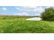 Spacious backyard with a pond, lush grass, and a distant view of neighborhood buildings at 14060 Princewood Dr, Fishers, IN 46037
