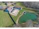 Aerial view of a home with large pond, pool, outdoor dining area, and well-maintained lawn at 1471 S Frog Pond Ct, Greenfield, IN 46140