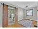 Bedroom with hardwood floors, sliding barn doors to laundry, and natural light from the window at 1707 Rocky Ford Rd, Columbus, IN 47203