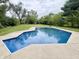 Inviting in-ground pool with clear blue water surrounded by concrete decking and lush green landscaping at 1707 Rocky Ford Rd, Columbus, IN 47203