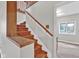 Staircase features wood stairs, a white wall, and a view into an adjacent room with hardwood flooring at 1707 Rocky Ford Rd, Columbus, IN 47203