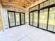 Covered patio area with multiple large black frame sliding glass doors and concrete flooring at 20598 Chatham Creek Dr, Westfield, IN 46074