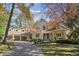 Charming stone home featuring a manicured lawn, mature trees, three-car garage, and inviting front porch at 2872 Jeremy Ct, Carmel, IN 46033