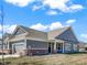 Exterior view of the gray home featuring a two-car garage, brick accents, and lush green lawn at 3124 Sharon Cir, Brownsburg, IN 46112
