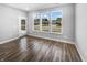 Living room with hardwood floors, three windows, and a door to a patio, offering a seamless indoor-outdoor flow at 3124 Sharon Cir, Brownsburg, IN 46112