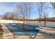 Backyard pool with safety cover, diving board, surrounded by concrete patio and white vinyl privacy fence at 5607 Regency Dr, Columbus, IN 47203