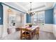 Bright dining room with blue walls, chandelier, wainscoting, and a view of another room at 5658 Pecan Ct, Noblesville, IN 46062