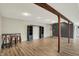 Open basement area featuring wood-look flooring, support beams, bar stools, and black shelving at 7023 Mustang Ct, Martinsville, IN 46151