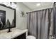 Modern bathroom featuring a vanity with sink, shower with gray curtain, and a decorative floral accent at 7023 Mustang Ct, Martinsville, IN 46151