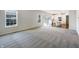 Bright and spacious living room with carpet flooring, neutral walls, and a view of the adjacent kitchen area at 733 Keepsake Run, Greenwood, IN 46143