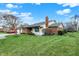 Backyard view showcasing the brick exterior, green lawn, and mature trees at 7607 Farm View E Cir, Indianapolis, IN 46256