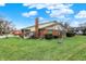 Backyard with a lush green lawn, a brick chimney, and mature shrubs at 7607 Farm View E Cir, Indianapolis, IN 46256