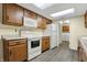 Kitchen with wood cabinets, white appliances, gray flooring, and a skylight at 7607 Farm View E Cir, Indianapolis, IN 46256