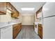 Kitchen features wood cabinets, white appliances, gray flooring, and a view of the dining area at 7607 Farm View E Cir, Indianapolis, IN 46256
