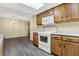 Kitchen features wood cabinets, white appliances, gray flooring, and a view of the dining area at 7607 Farm View E Cir, Indianapolis, IN 46256
