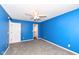 Spacious bedroom with blue walls, gray carpet, and a ceiling fan, with a door that leads to a walk-in closet at 12527 Trester Ln, Fishers, IN 46038