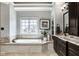 Relaxing bathroom featuring a soaking tub, vanity with granite countertop, and natural light at 12897 Queens Troop, Carmel, IN 46032