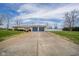 Long concrete driveway leads to a ranch-style house with a two-car garage on a vast lawn at 140 Kim Dr, Anderson, IN 46012