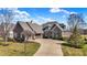 Beautiful stone home with a curved driveway and manicured lawn, accented with lovely trees under a bright blue sky at 16129 Brookhollow Dr, Westfield, IN 46062