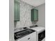 Functional laundry room with floral wallpaper, green cabinets, and modern Maytag washer and dryer at 19970 Edwick Dr, Westfield, IN 46074