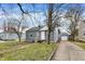 View of a one-story home and detached garage with gray siding, white trim, and inviting curb appeal at 5309 E 19Th Pl, Indianapolis, IN 46218