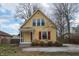 Charming two-story yellow home featuring a cozy front porch and mature trees at 5915 Lowell Ave, Indianapolis, IN 46219