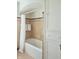 Clean bathroom with tan tiling, bathtub, shower curtain, and white storage shelves at 6105 E St Joseph St, Indianapolis, IN 46219