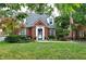 Charming brick home with a well-manicured front yard, mature trees, and an American flag at 6105 E St Joseph St, Indianapolis, IN 46219