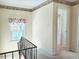 Hallway featuring black railings, wallpaper border, and a view into a vintage-style bathroom at 6105 E St Joseph St, Indianapolis, IN 46219