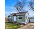 View of a cozy single-story home with light green siding and a detached garage at 621 Melvenia St, Indianapolis, IN 46219