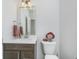 Well-lit bathroom featuring a vanity with a sink, a large mirror, and a clean, modern toilet at 6609 N Dogwood Dr, McCordsville, IN 46055