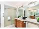 Well-lit bathroom with a glass door shower, wood cabinets and a large mirror over the sink at 7160 Harbour, Indianapolis, IN 46240