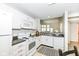 Bright kitchen features white appliances and cabinets, dark countertops, and a view of the living room at 7160 Harbour, Indianapolis, IN 46240