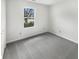 Bright bedroom with a window showcasing outdoor views and plush gray carpet flooring at 7228 Muirfield Pl, Indianapolis, IN 46237