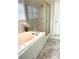 Bright bathroom showcasing a jacuzzi tub, glass shower, neutral tiled walls and floors, and gold hardware at 12652 Meeting House Rd, Carmel, IN 46032