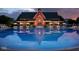 Stunning community pool with umbrellas and chairs reflects the adjacent clubhouse at twilight at 12652 Meeting House Rd, Carmel, IN 46032