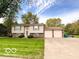Split level home features a large manicured lawn, mature trees, and an attached two-car garage at 1402 Hornaday Rd, Brownsburg, IN 46112