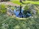 Close up of backyard pond surrounded by lush greenery and decorative rock border at 1402 Hornaday Rd, Brownsburg, IN 46112