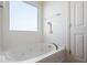 Bright bathroom featuring a jetted bathtub, modern fixtures, and natural light from a frosted window at 15152 Fallen Leaves Ln, Noblesville, IN 46060