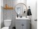 Modern bathroom features a patterned accent wall, floating shelf, vanity with round mirror, and gray cabinet at 15152 Fallen Leaves Ln, Noblesville, IN 46060