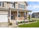 Close up of the inviting covered front porch with brick facade and black rocking chair at 15152 Fallen Leaves Ln, Noblesville, IN 46060