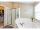 This bathroom features a large soaking tub with tile surround and a glass-enclosed shower, with a gray bathmat on the floor at 15885 Symphony Blvd, Noblesville, IN 46060