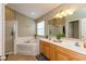This well-lit bathroom features an oval soaking tub, a walk-in shower, and a double sink vanity with a mirror at 15885 Symphony Blvd, Noblesville, IN 46060